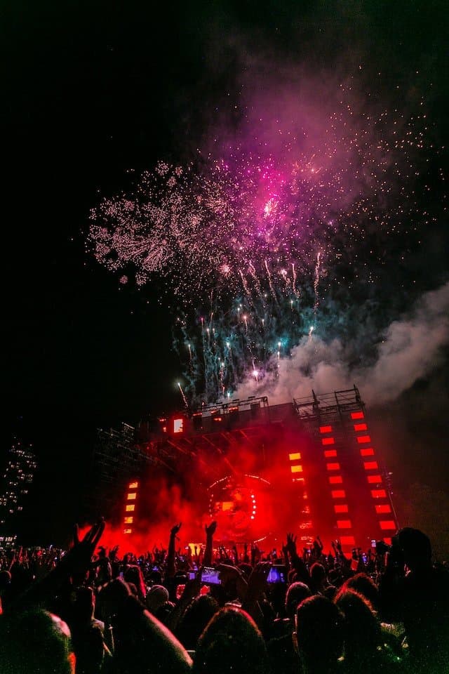 Fireworks display over a concert stage at night